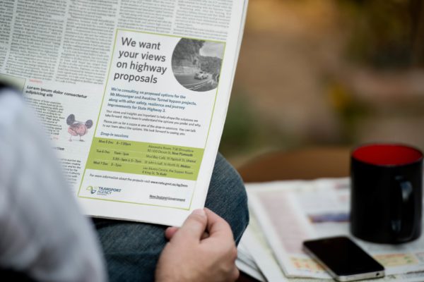 Man holding a newspaper with a public engagement advert created by comms strategists Wonderlab.
