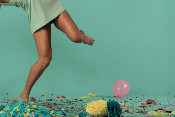 A woman jumping in front of confetti and balloons.
