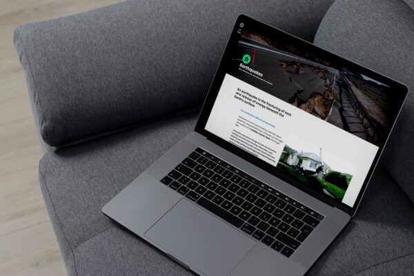 A laptop with a website on it sitting on a couch.