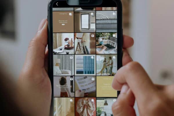 A person is holding a smartphone displaying an Instagram profile with a grid of various home decor-related posts.